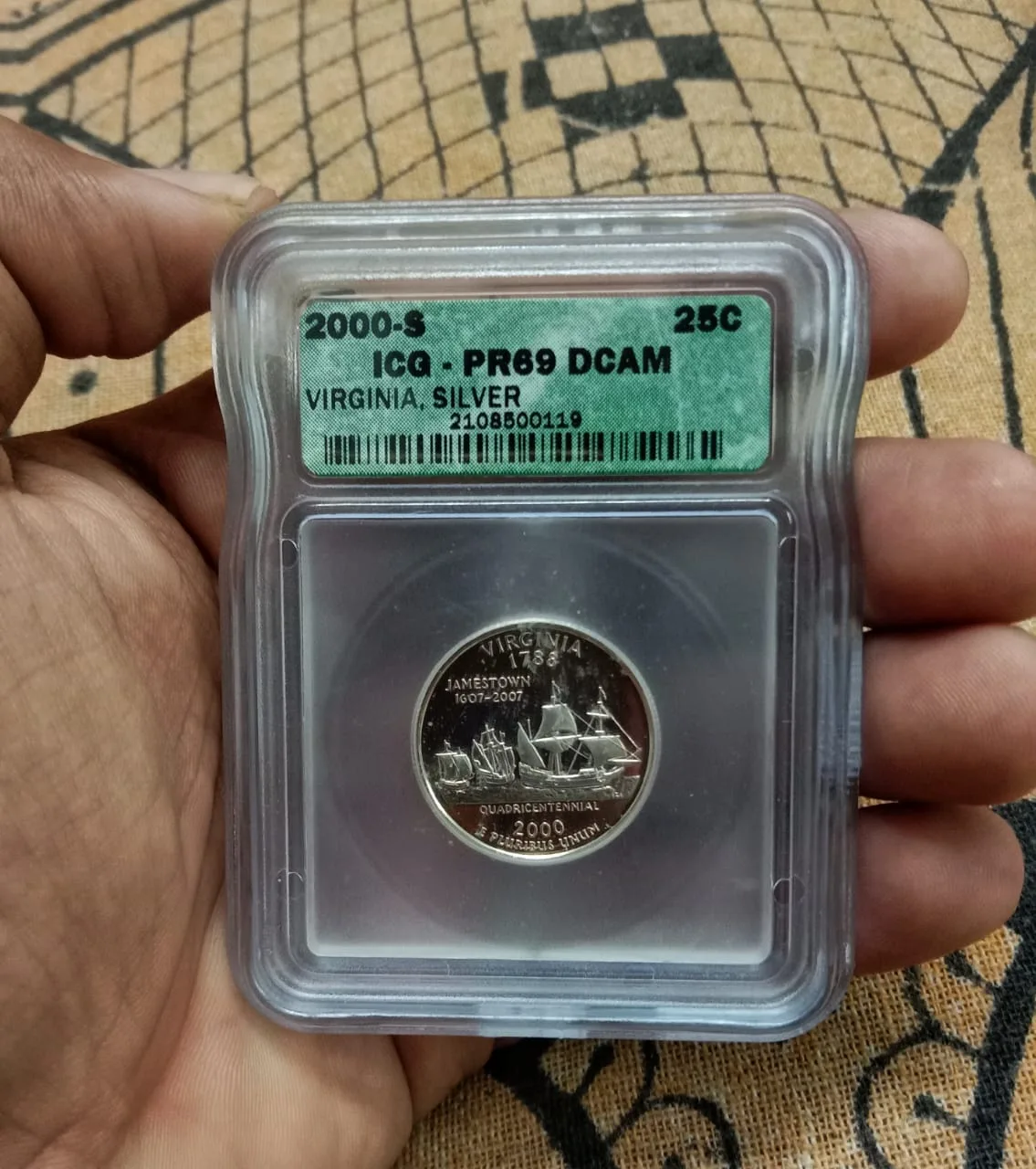 A hand holding a 2000-S Virginia silver proof quarter sealed in an ICG holder, the label reading 2000-S, ICG PR69 DCAM, VIRGINIA, SILVER