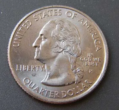 Obverse of a 2005-P Kansas quarter photographed at an angle, the motto reading IN GOD WE RUST with the T of TRUST entirely absent