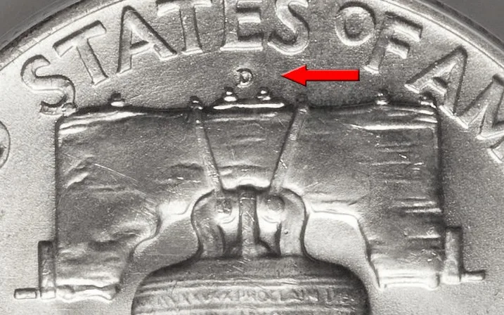 Close view of the top of a Franklin half dollar reverse with a red arrow pointing at the D mint mark, which sits between the bell's yoke and the words STATES OF AMERICA