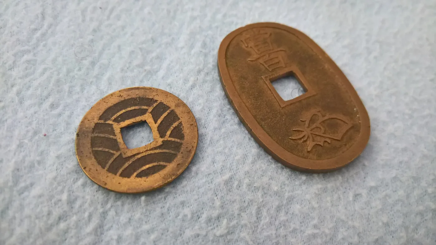 Reverses of a four-mon Kan'ei Tsuho showing its wave pattern and an oval Tenpo Tsuho showing the value characters and the kao cipher