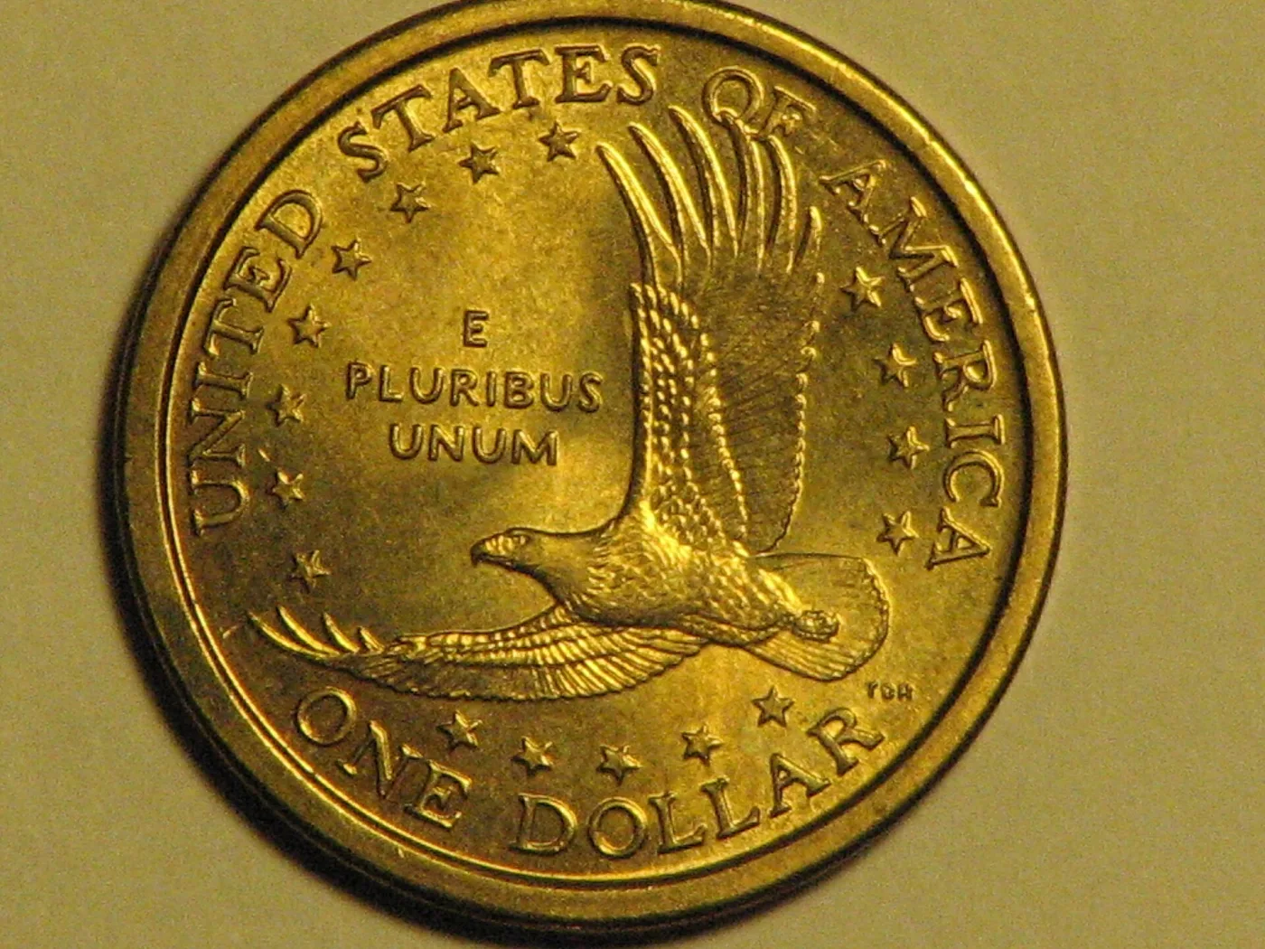 Reverse of a circulated Sacagawea dollar photographed in the hand, the soaring eagle with E PLURIBUS UNUM in the field and ONE DOLLAR below