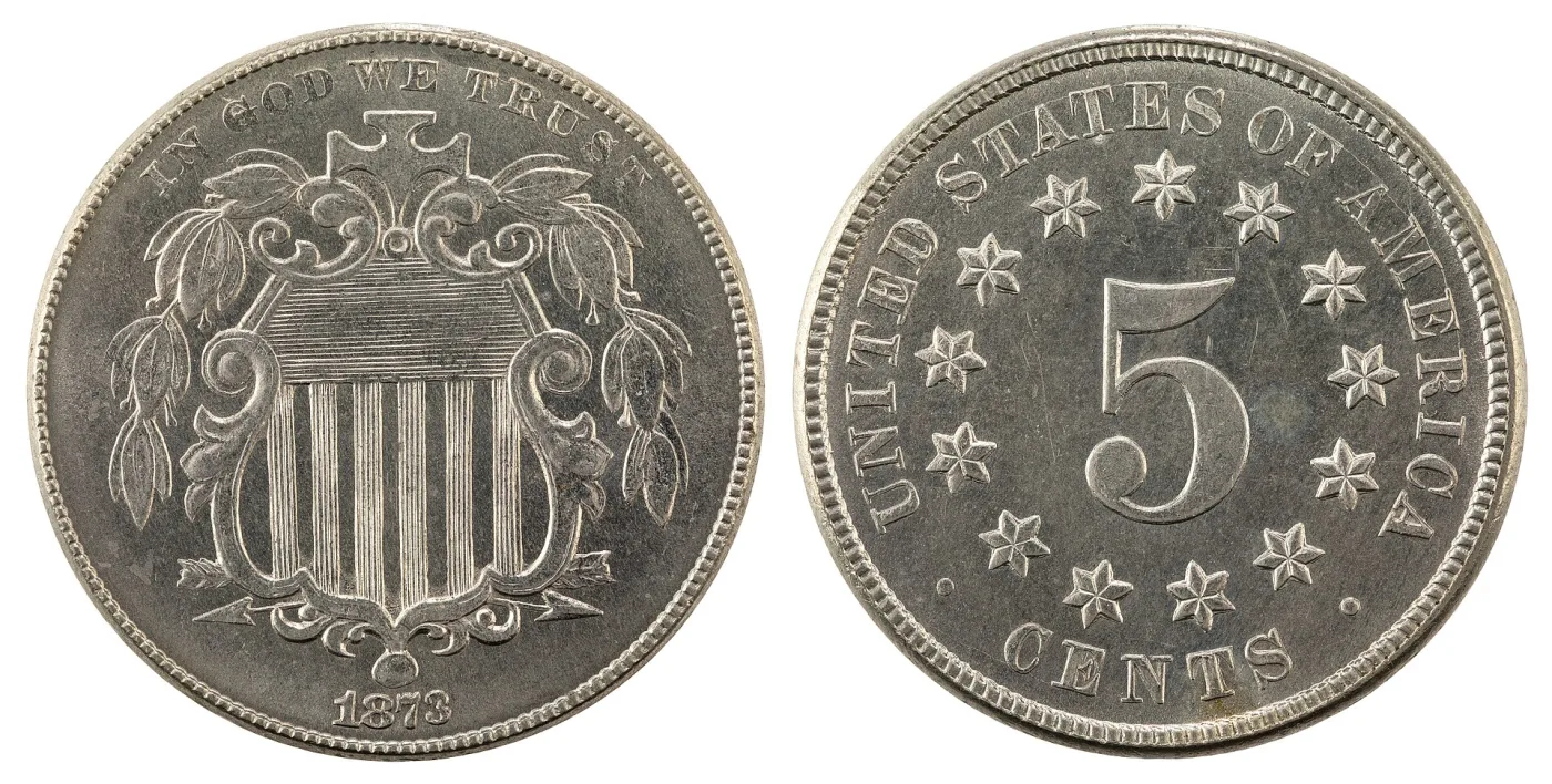 Obverse and reverse of an 1873 Shield nickel shown side by side, the obverse carrying the federal shield under IN GOD WE TRUST and the reverse a large numeral 5 ringed by thirteen stars