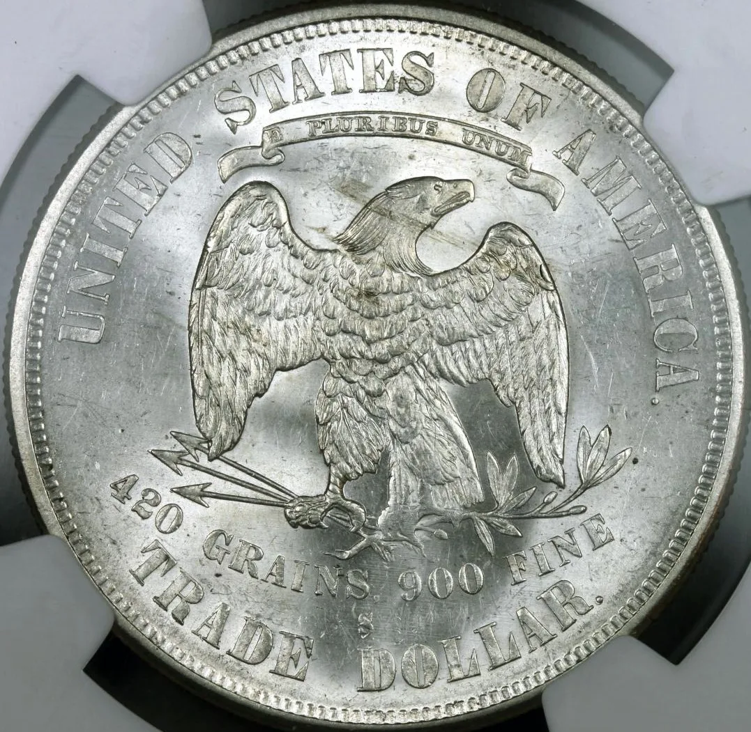 Reverse of an 1874-S Trade Dollar in a grading holder, the olive branch berry sitting above the eagle's claw and the S mint mark above TRADE DOLLAR